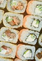 detailopname van een veel van sushi broodjes met verschillend vullingen. macro schot van gekookt klassiek Japans voedsel. achtergrond beeld foto