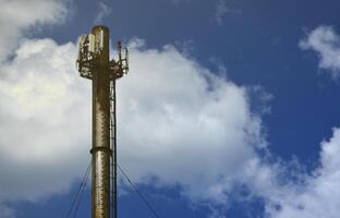 hoog metaal schoorsteen van industrieel fabriek met ladder in de het formulier van metaal een beugel tegen de achtergrond van een bewolkt blauw lucht foto