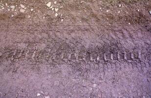 wiel bijhouden Aan modder. sporen van een trekker of zwaar van de weg af auto Aan bruin modder in nat weide foto