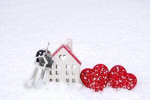 sleutels van klein huis en twee harten in sneeuw - Valentijnsdag dag, liefde in huis. paar huisvesting, echt landgoed, huur, hypotheek, verhuizing. comfort en warmte in liefde nest. foto