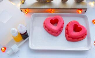 handgemaakt eigengemaakt zeep in de vorm van harten voor een Valentijnsdag dag geschenk naar uw geliefde. parfums en kleurstoffen, zeep baseren Aan de tafel foto