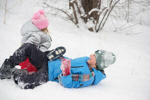 een meisje en een jongen in een besneeuwd Woud zijn rijden een ijs glijbaan naar beneden een schuiven. foto van een kind in een winter Woud. winter, winter vakantie, vakanties, vakanties.