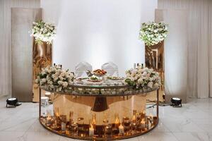 romantisch tafel instelling in een restaurant voor een vakantie. bruiloft decor voor de pasgetrouwden Bij de banket. bloemisterij van vers bloemen en kaarsen, boho stijl. catering voor de bruid en gasten. foto