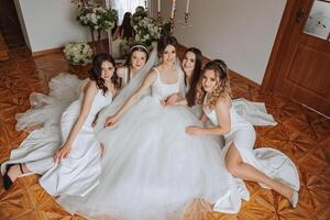 vrienden verheugen met de bruid in de ochtend. ze nemen afbeeldingen, glimlach, helpen de bruid vastmaken haar jurk. foto