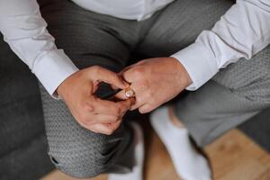 Mannen de elite ring gemaakt van goud met een diamant. mannetje handen elementen met ring en pinnen detailopname. een Mens is voorbereidingen treffen voor een evenement. foto