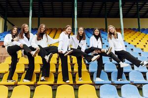 een groep van veel gelukkig tieners gekleed in de dezelfde kleding hebben pret en poseren in een stadion in de buurt een middelbare school. concept van vriendschap, momenten van geluk. school- vriendschap foto