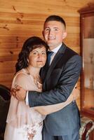 moeder helpt haar volwassen zoon bereiden voor de bruiloft ceremonie. een emotioneel en aanraken moment Bij een bruiloft. een moeder knuffels haar zoon foto