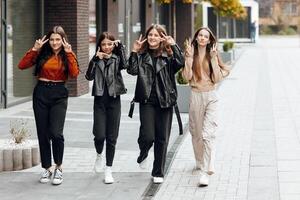 groep van glimlachen en gelukkig tiener- vrienden vervelend gewoontjes kleren uitgeven tijd samen, poseren en pratend met elk andere in de buurt college gebouw Aan herfst dag. foto