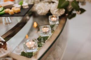 romantisch tafel instelling in een restaurant voor een vakantie. bruiloft decor voor de pasgetrouwden Bij de banket. bloemisterij van vers bloemen en kaarsen, boho stijl. catering voor de bruid en gasten. foto