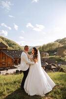 bruiloft. liefde en paar in tuin voor bruiloft. viering van ceremonie en inzet. opslaan de datum. vertrouwen. de bruidegom omarmt de bruid tegen de achtergrond van een hotel in de bergen. foto