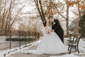 winter bruiloft. gelukkig paar wandelen in bruiloft kleren knuffelen en glimlachen in een winter park gedekt met sneeuw Aan hun bruiloft dag. winter liefde verhaal van een mooi paar in besneeuwd winter weer foto