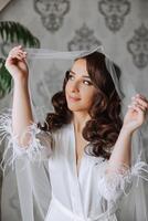 een mooi brunette bruid met een tiara in haar haar- is krijgen klaar voor de bruiloft in een mooi gewaad in boudoir stijl. detailopname bruiloft portret, foto. foto