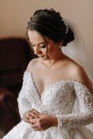 de bruid in haar bruiloft jurk poses in haar kamer. portret van de bruid Open schouders en halslijn. foto