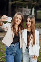 twee jong Dames nemen een selfie met een slim mobiel telefoon buitenshuis - gelukkig mooi vrouw vrienden glimlachen Bij de camera buitenshuis - levensstijl concept met vrolijk meisjes genieten van buitenshuis recreatie. foto