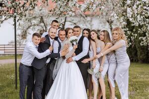 volledige lengte portret van de pasgetrouwden en hun vrienden Bij de bruiloft. de bruid en bruidegom met bruidsmeisjes en vrienden van de bruidegom zijn hebben pret en verheugt Bij de bruiloft. foto