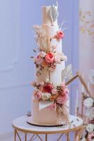 een meerlagig bruiloft taart in de banket hal, versierd met vers bloemen. voorbereiding voor de bruiloft viering. snijdend de bruiloft taart. foto