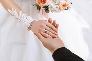 de bruidegom teder houdt de bruid hand- na plaatsen een bruiloft ring Aan haar vinger Bij een bruiloft ceremonie. een mooi bruiloft in de verkoudheid seizoen. foto