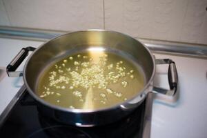 Koken pot met olie en in blokjes gesneden knoflook foto