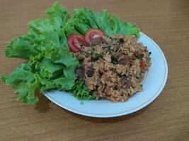 heerlijk Indonesisch gebakken rijst- nasi goreng met veel van sla, mosterd Groenen en tomaten geserveerd Aan een wit bord foto