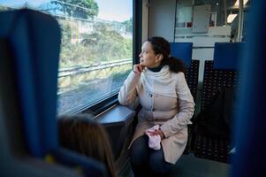 attent jong vrouw op reis door trein, dromerig op zoek uit de venster, genieten van haar comfortabel het spoor weg reis foto