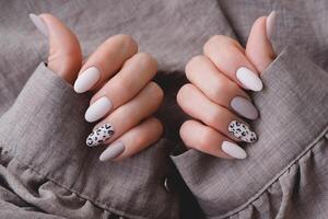 vrouw hand- met een mooi ovaal van vorm manicuren. herfst tendens, beige kleur polijsten met luipaard patroon Aan nagels met gel Pools, schellak. foto