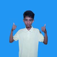 Aziatisch Mens glimlachen gezicht met Oke gebaar, geïsoleerd Aan blauw achtergrond foto