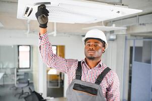 gelukkig jong Afrikaanse mannetje technicus repareren lucht conditioner foto