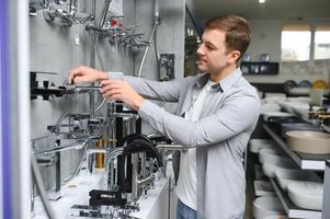 Mens kiest een badkamer kraan in een bouw supermarkt, loodgieter reparaties in de huis foto