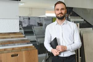 portret van een keramisch tegel verkoper. de verkoper staat tegen de achtergrond van een groot assortiment van tegels foto