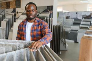 Afrikaanse Amerikaans Mens klant kiezen keramisch tegel Bij gebouw materialen op te slaan foto