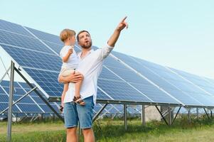 gelukkig vader en zijn weinig zoon zijn wandelen in de buurt de zonne- panelen. de concept van groen energie. foto