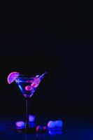 martini glas en olijven Aan een zwart achtergrond met neon lichten foto