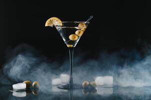 glas van klassiek droog martini cocktail met olijven Aan donker tafel tegen zwart achtergrond. met vrij ruimte voor uw tekst foto