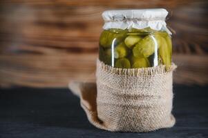 gepekeld komkommers in de kan. ingrediënten voor beitsen komkommers. komkommers, dille, knoflook. glas potten met augurken foto