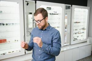 schot van een knap gebaard Mens proberen Aan nieuw bril Bij de eyewear winkel.man buying bril.gezondheid, gezichtsvermogen, visie, mode, boodschappen doen foto