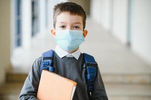 weinig schooljongen vervelend een masker gedurende een het uitbreken van corona en influenza virus, bescherming tegen ziekten voor kinderen, masker voor de het voorkomen van coronavirus foto