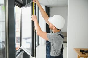 knap jong Mens installeren baai venster in nieuw huis bouw plaats foto