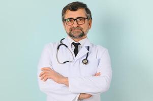senior dokter Mens vervelend stethoscoop en medisch jas over blauw achtergrond foto