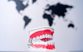 verkennen mondeling Gezondheid in de omgeving van de wereldbol. een plastic model- van een mond met een tandenborstel in voorkant van een wereld kaart foto