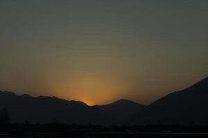 een zonsondergang over- bergen foto