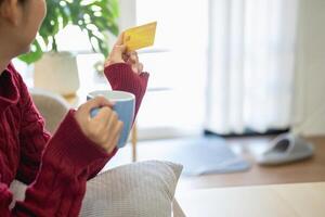 een jong Aziatisch vrouw met een gelukkig glimlach houdt een credit kaart en toepassingen een smartphone naar winkel online online betaling concept. foto