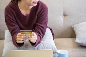 mooi Aziatisch Dames gebruik makend van credit kaarten voor boodschappen doen online met laptops en smartphones, online boodschappen doen portret concept. foto