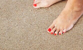 vrouwen voeten met een pedicure in de zand Aan de strand foto