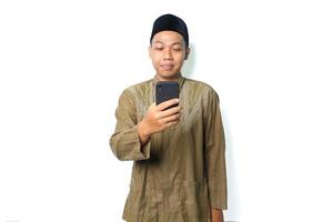 verheugd Aziatisch moslim Mens lezen een bericht gebruik makend van mobiel telefoon geïsoleerd Aan wit achtergrond foto