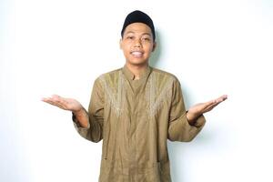 glimlachen Aziatisch moslim Mens vervelend Islamitisch jurk uitrekken hand- terzijde naar presenteren leeg ruimte met Open palm geïsoleerd Aan wit achtergrond foto