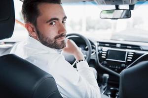 zelfverzekerde jonge zakenman achter het stuur van zijn nieuwe auto foto