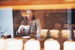 mooie jonge vrouw zit in het café met een kopje thee foto