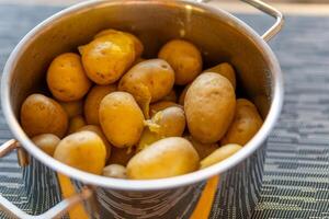 een Koken pot met ongeschild gekookt aardappelen foto