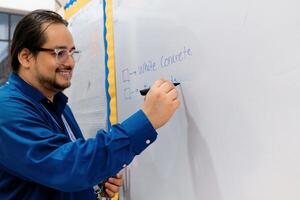 portret van glimlachen Engels leraar kronkelend met maker Aan de whiteboard. foto
