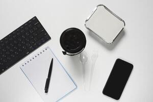 een wit bureau met een laptop, telefoon, en een kop van koffie foto